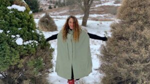 Lara walking between pine trees in a snowy field