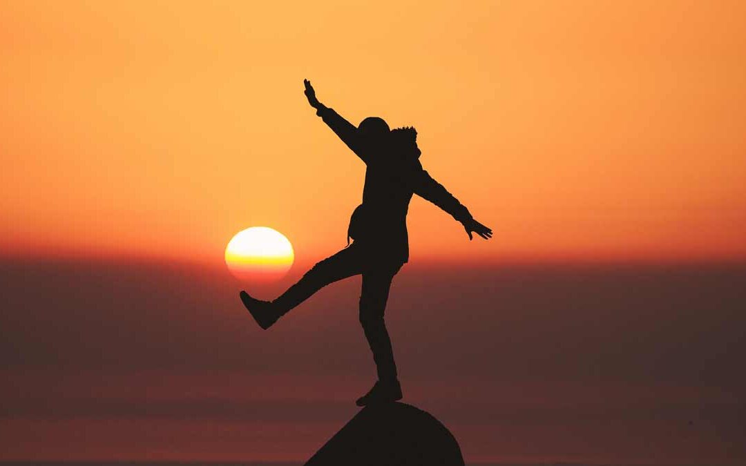 Woman standing on a mountain top at sunset