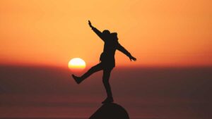 Woman standing on a mountain top at sunset